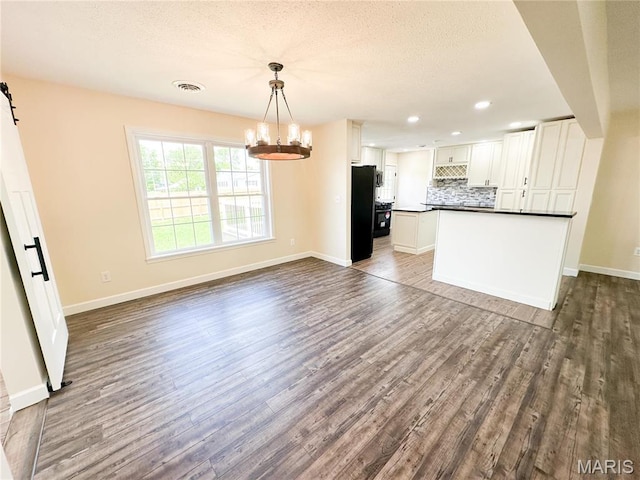 906 E Pace St, Salem, MO 65560 - kitchen featuring dark countertops, tasteful backsplash, freestanding refrigerator, a chandelier, and dark wood-type flooring