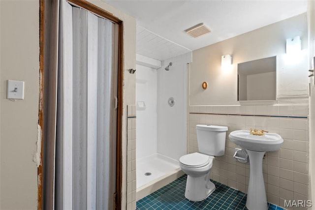 1095 Rogers Ln, Florissant, MO 63033 - bathroom with tile patterned flooring, toilet, a shower stall, tile walls, and a wainscoted wall