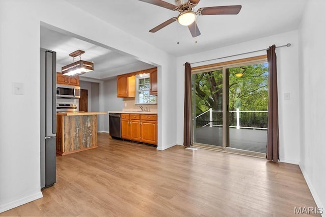 kitchen featuring stainless steel appliances, light countertops, light wood-type flooring, and a ceiling fan