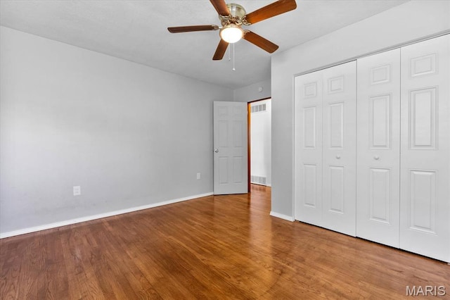 unfurnished bedroom featuring wood finished floors, baseboards, a closet, and ceiling fan