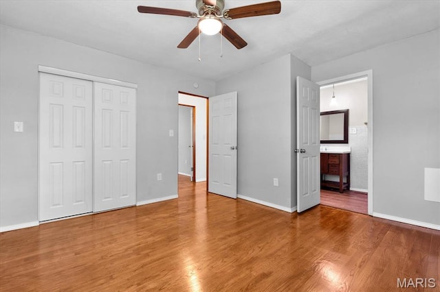 unfurnished bedroom with wood finished floors, baseboards, and a closet