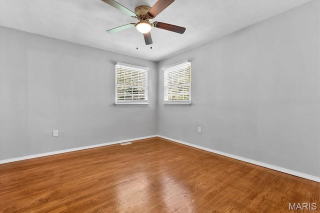 unfurnished room with wood finished floors, baseboards, and a ceiling fan