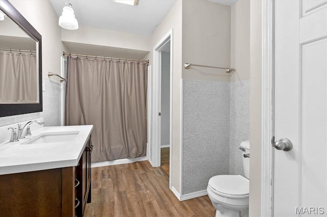 bathroom with wood finished floors, vanity, toilet, and curtained shower