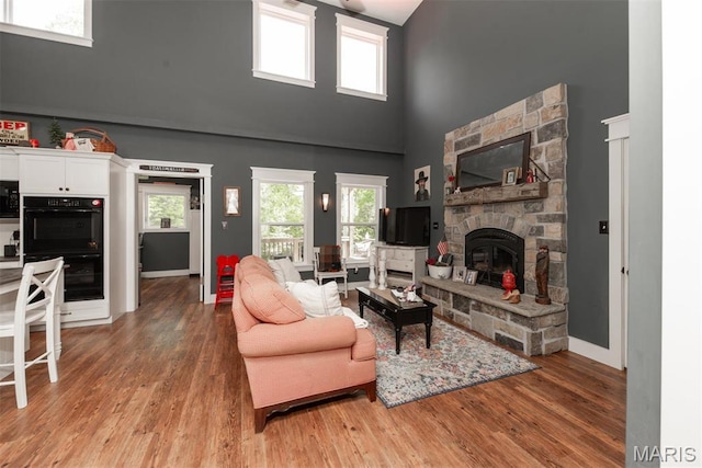 7877 Sylvan Pl, Dittmer, MO 63023 - living area featuring a high ceiling, light wood-style flooring, a stone fireplace, and baseboards