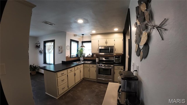 kitchen with stainless steel appliances, dark countertops, a peninsula, a sink, and recessed lighting