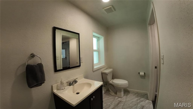 bathroom featuring marble look tiles, vanity, and toilet