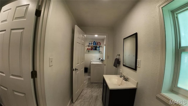 half bathroom featuring washer / dryer, vanity, toilet, and healthy amount of natural light