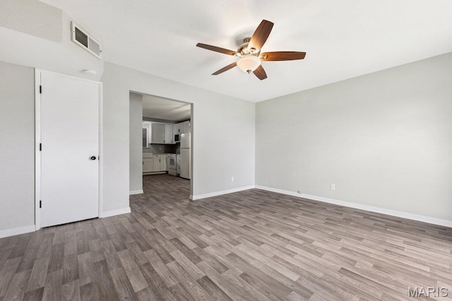 unfurnished living room featuring a ceiling fan, wood finished floors, and baseboards