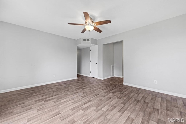 spare room featuring a ceiling fan, wood finished floors, and baseboards