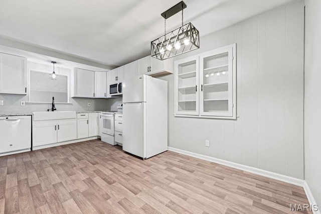 kitchen with white appliances, a sink, baseboards, and light wood-type flooring