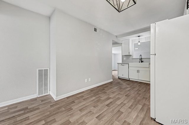 kitchen with white appliances, white cabinetry, light wood finished floors, and baseboards
