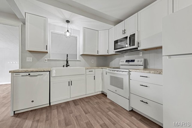 kitchen featuring white appliances, a sink, light countertops, white cabinets, and light wood-style flooring