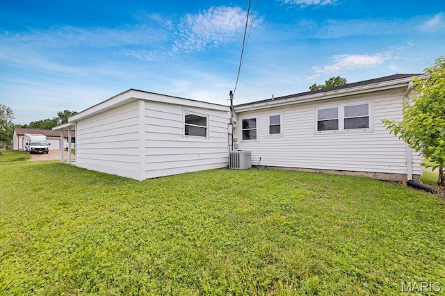 rear view of house with central AC and a yard