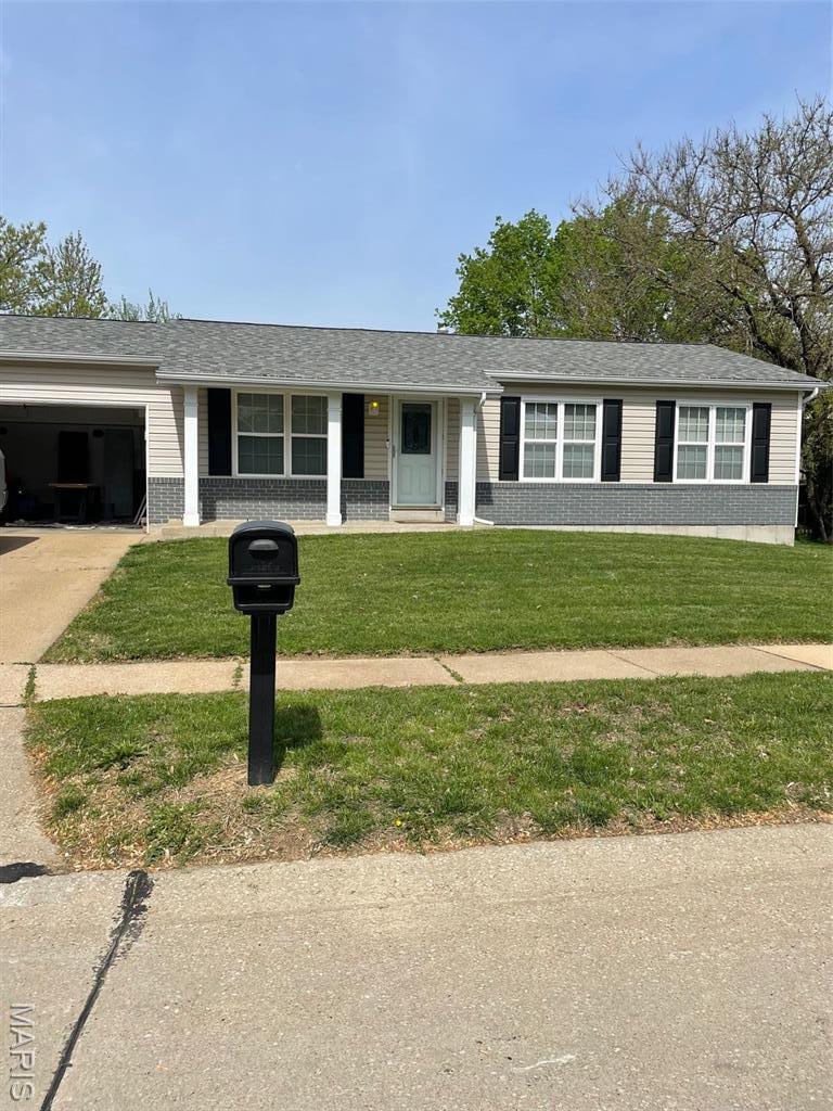 single story home featuring an attached garage, a front yard, concrete driveway, and roof with shingles
