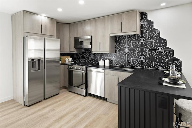 7544 Melrose Ave, University City, MO 63130 - kitchen with stainless steel appliances, a sink, dark countertops, tasteful backsplash, and light wood-style floors