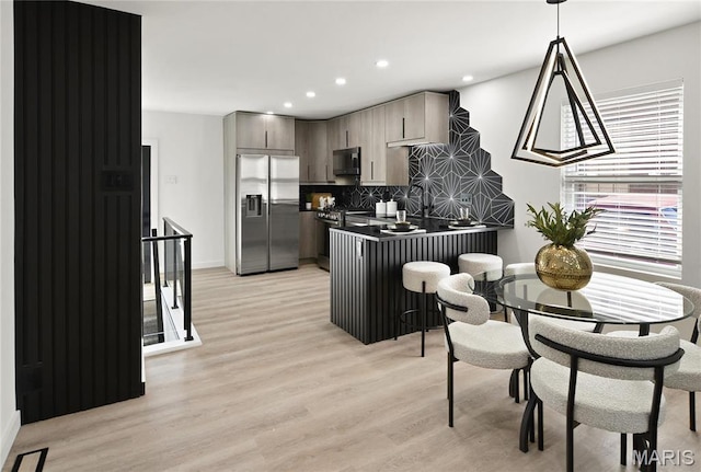 7544 Melrose Ave, University City, MO 63130 - kitchen with appliances with stainless steel finishes, dark countertops, a peninsula, light wood-type flooring, and tasteful backsplash