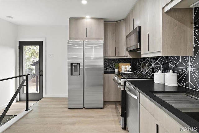 7544 Melrose Ave, University City, MO 63130 - kitchen featuring appliances with stainless steel finishes, dark countertops, light wood-type flooring, tasteful backsplash, and recessed lighting