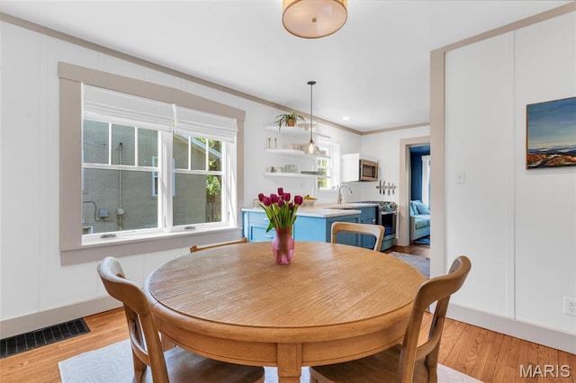 dining room featuring light wood finished floors and ornamental molding