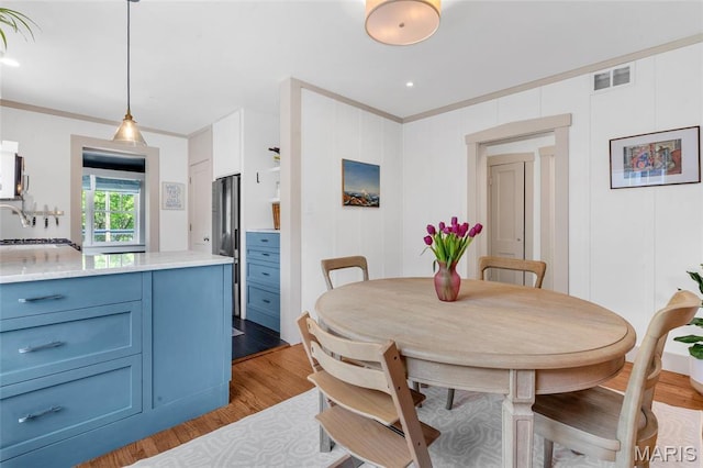 dining space with ornamental molding and wood finished floors