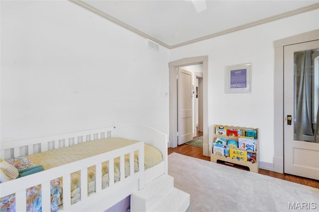 bedroom featuring crown molding, wood finished floors, and baseboards