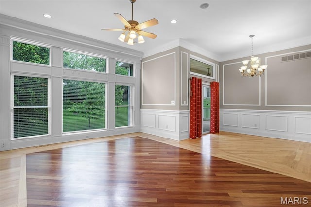 unfurnished dining area featuring a decorative wall, a chandelier, wood finished floors, a ceiling fan, and recessed lighting