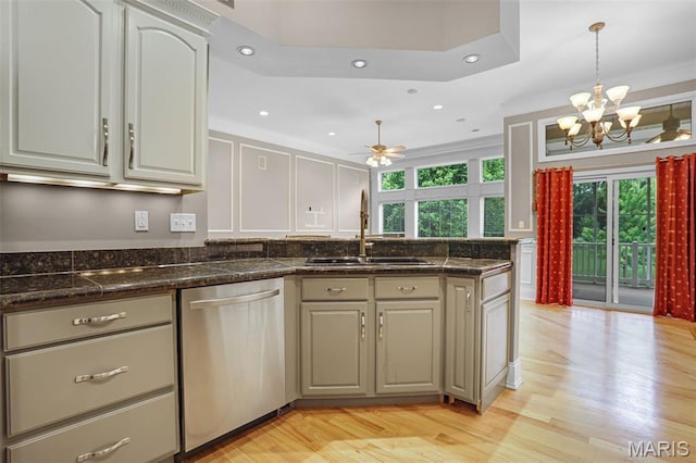 kitchen featuring dishwasher, a sink, a peninsula, light wood finished floors, and a chandelier