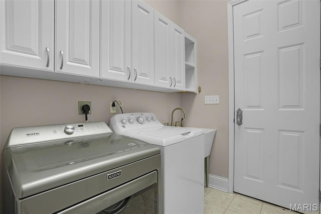 washroom featuring cabinet space, washing machine and dryer, light tile patterned floors, and baseboards