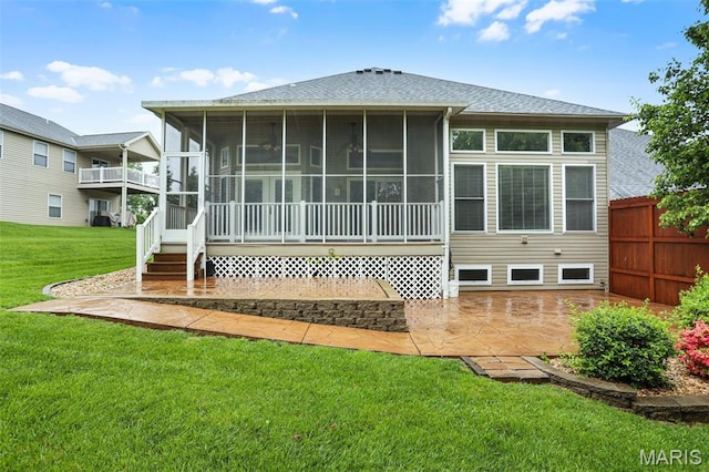 back of house with roof with shingles, a sunroom, and a patio area