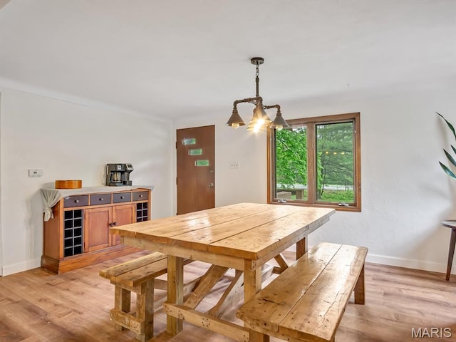 dining space with light wood-type flooring, a chandelier, and baseboards