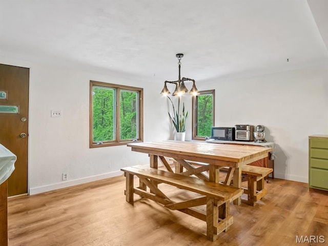 dining space with healthy amount of natural light, light wood finished floors, a chandelier, and baseboards