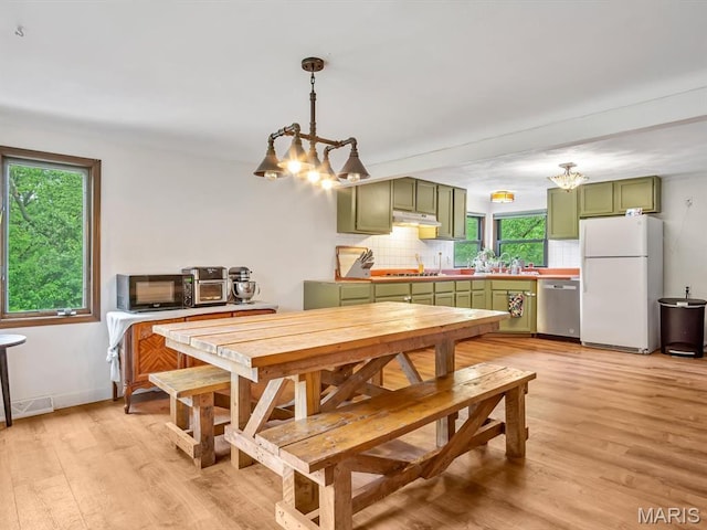 dining room with a chandelier, plenty of natural light, and light wood-style floors