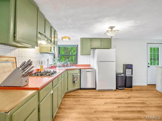 kitchen featuring green cabinetry, stainless steel appliances, under cabinet range hood, and decorative backsplash