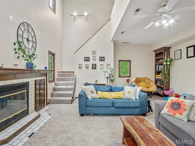 carpeted living room with stairway, a fireplace, and a ceiling fan