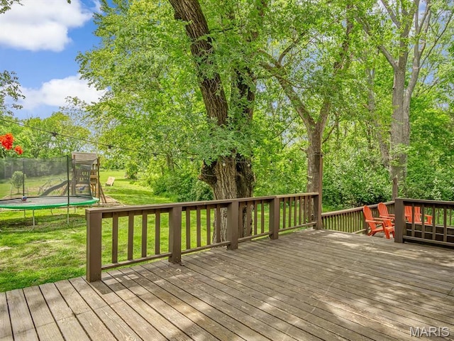 wooden deck featuring a trampoline and a lawn