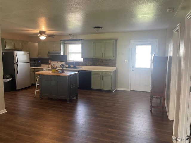 kitchen featuring black appliances, a textured ceiling, ceiling fan, dark wood finished floors, and a center island
