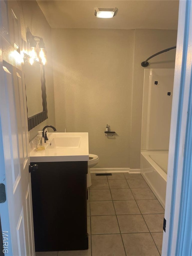 bathroom featuring tile patterned flooring, vanity, toilet, baseboards, and shower / bath combination