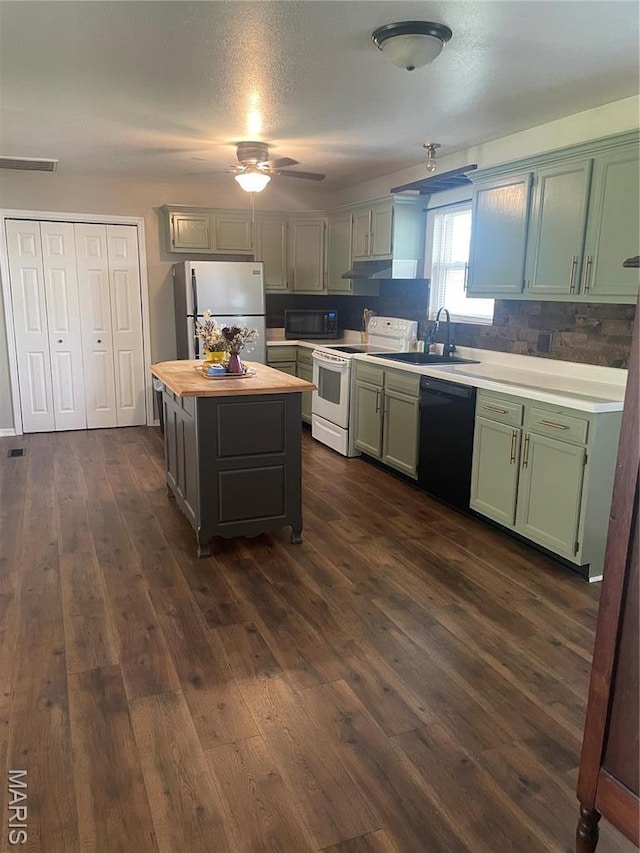 kitchen featuring black appliances, a sink, ceiling fan, dark wood-type flooring, and a center island