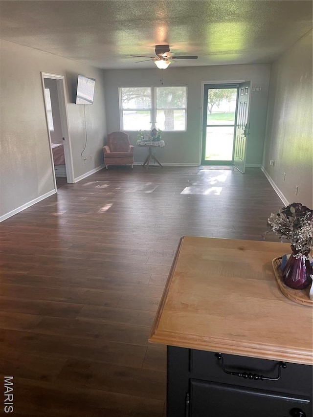 dining space with healthy amount of natural light, a ceiling fan, dark wood-style floors, baseboards, and a textured ceiling
