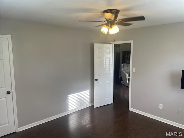 empty room with a ceiling fan, baseboards, and dark wood-type flooring