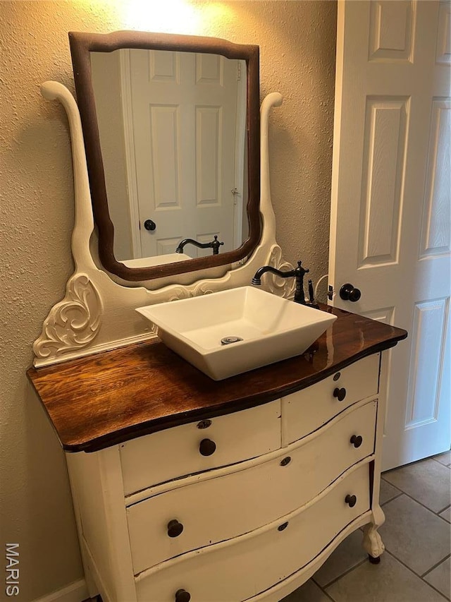 bathroom with vanity, tile patterned flooring, and a textured wall