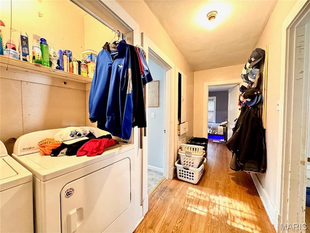 washroom with washing machine and dryer, wood finished floors, and baseboards