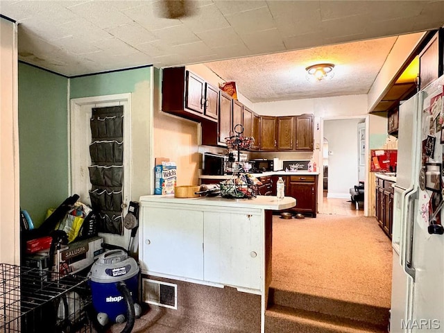 kitchen with white refrigerator with ice dispenser, a peninsula, light countertops, and light carpet