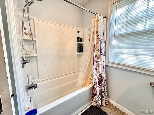 bathroom featuring shower / tub combo and baseboards