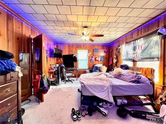bedroom featuring wood walls, an office area, and carpet