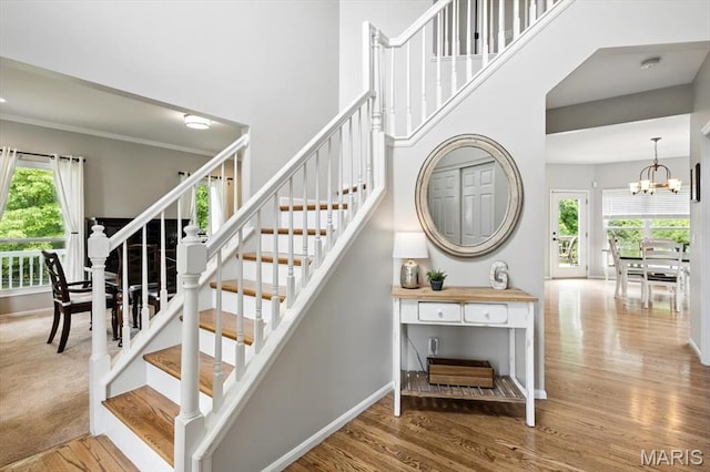 stairs with plenty of natural light, wood finished floors, and a towering ceiling