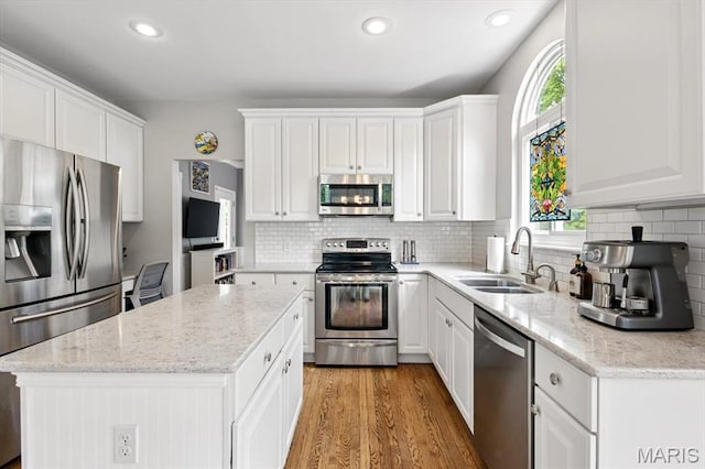 kitchen featuring appliances with stainless steel finishes, a sink, white cabinets, a center island, and recessed lighting