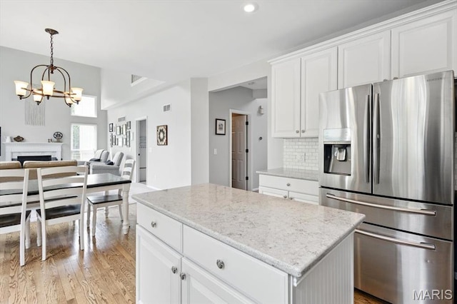 kitchen with stainless steel refrigerator with ice dispenser, light wood finished floors, open floor plan, a chandelier, and recessed lighting
