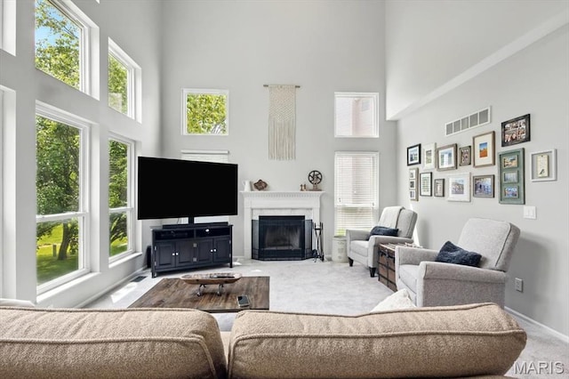 carpeted living room featuring a high ceiling, a glass covered fireplace, and baseboards