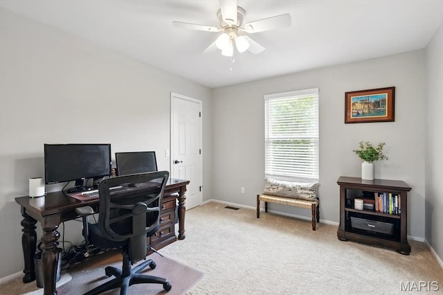 home office featuring light colored carpet, baseboards, and a ceiling fan