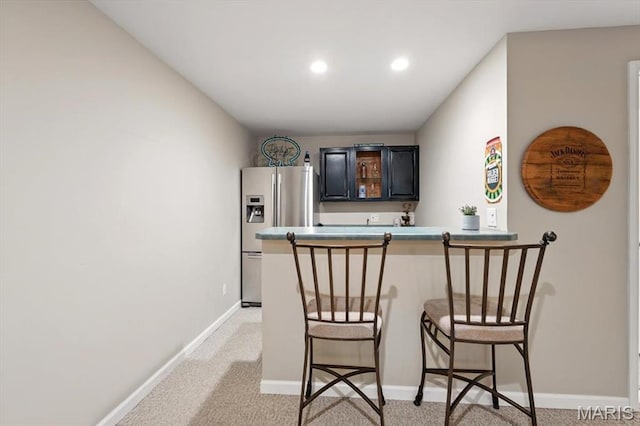 indoor wet bar with stainless steel refrigerator with ice dispenser, light carpet, recessed lighting, and baseboards